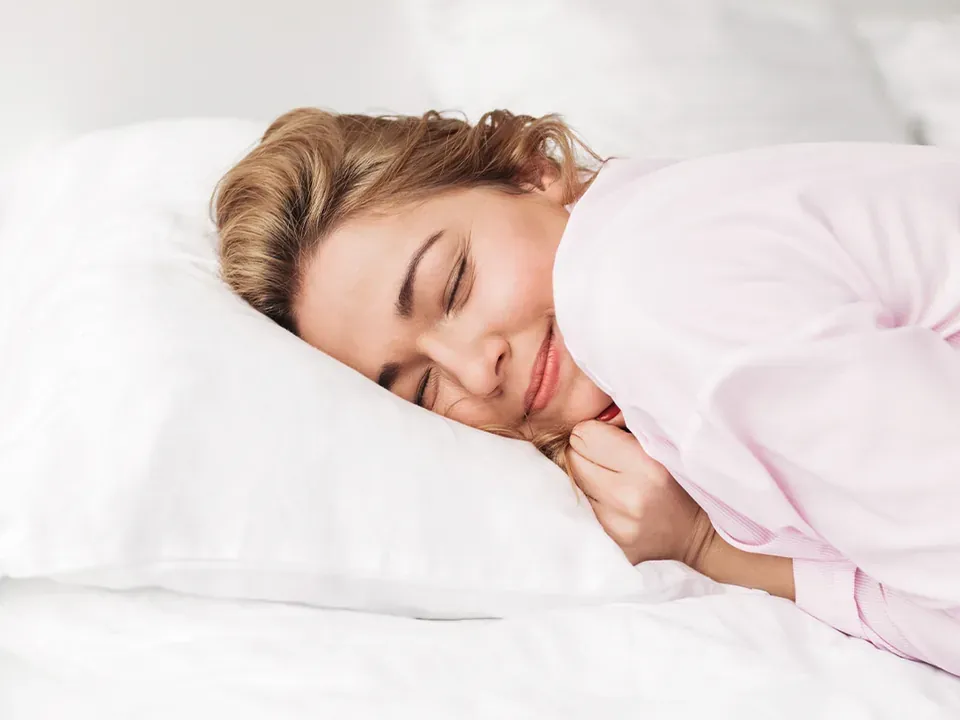 A woman asleep on her side on a white pillow