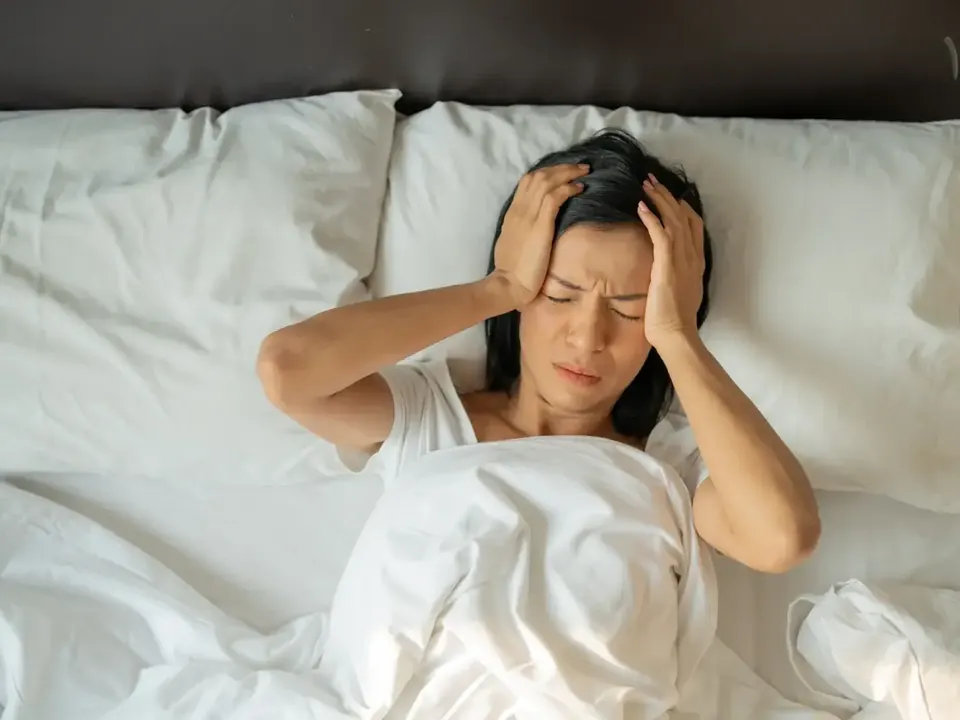 Stressed woman sitting in bed holding her head in her hands