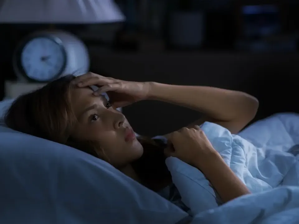 Woman wide awake late at night beside her bedside clock